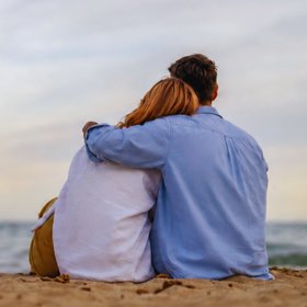 Paar sitzt umarmt am Strand